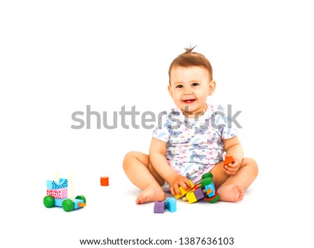 Cute happy baby with wooden developmental toy isolated on white background. Picture of crawling curious baby.