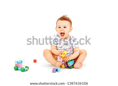 Cute happy baby with wooden developmental toy isolated on white background. Picture of crawling curious baby.