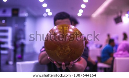 A boy holding a gold bowling ball at the bowling alley get ready to strike. This sport or game is call ten-pins bowling.