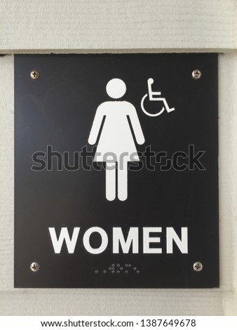 Black background woman’s restroom sign with a woman icon handicapped accessible and braille