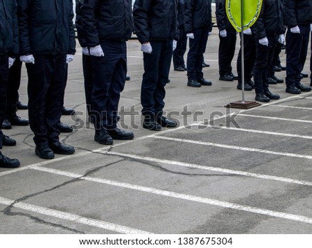 Side view of a group of soldiers or policemen in white gloves who stand in the ranks. Legs in black uniform and coarse army boots. Military parade.