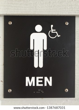 Close up of a Black men’s restroom sign with man handicap accessible with the braille
