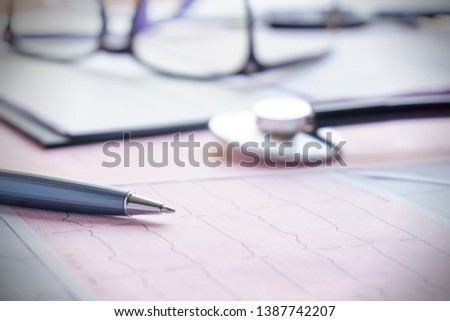 the stethoscope, the glasses and the pen lie on the cardiogram.  medical concept