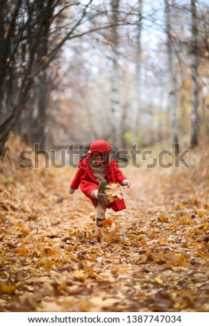 A girl in a red coat and felt hat walks merrily through the autumn forest, golden autumn, childhood and loneliness