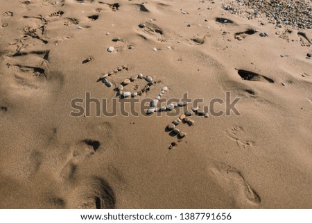 The word "love" laid out with pebbles on a spit near the ocean is washed by waves