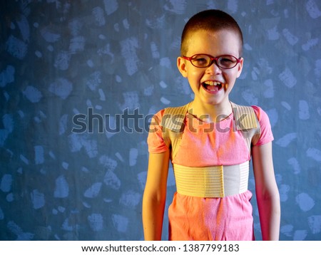 Kid in corrector for spine in pink t-shirt on a gray background 
Child wearing back support belt for support and improve back posture