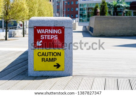 Two warning signs "Warning steps" and "Caution ramp" beside each other illustrating the phrase "Health and Safety gone mad."