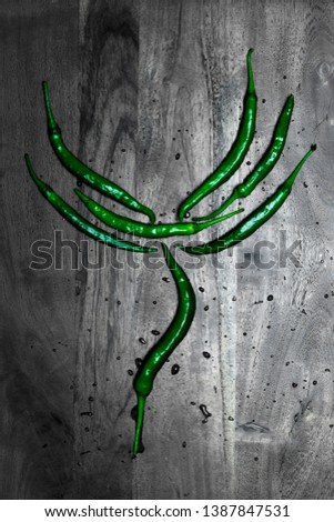 Green chillies laid out in a design on a dark background