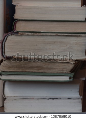 A stack of old books on the shelf. Texture pages of old books close up. Vertical photo