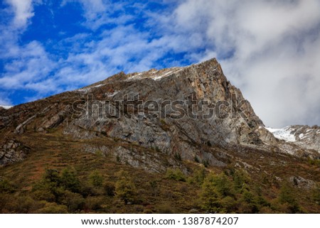 Mountain Cliffs, Jagged Steep Rock Face, extreme vertical drop, Blue Sky White Clouds in Background, Landscape Graphic Image.