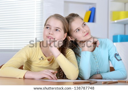 young twins drawing together at the table at home