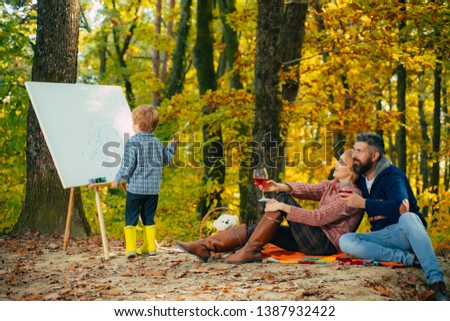 Talent development. Painting skills. Mom and dad relax park picnic while kid painting. Rest and hobby concept. Parents watching their little son painting picture in nature. Art and self expression.