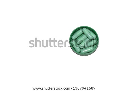 Group of green medical capsules on green lid,isolated on white with clipping path