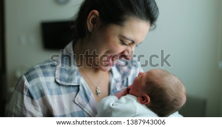 Mother holding newborn baby kissing infant, showing love after birth