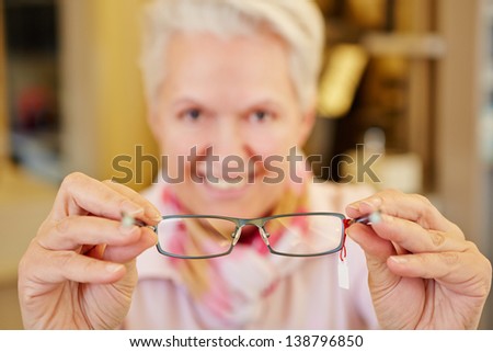 Smiling senior optician holding new glasses in her hands Royalty-Free Stock Photo #138796850