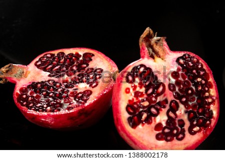 cut ripe pomegranate, sweet grains on a black background