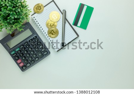 Top view of white office desk with Golden Bitcoins (Cryptocurrency) ,notepad,Calculator,Credit Cards. Top view with copy space