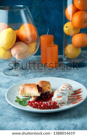 Sliced homemade berry strudel served with fresh red currant berries and powdered sugar on an old background on a plate with ice cream pic