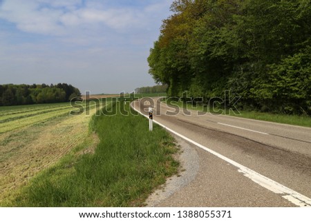 Spring landscape with asphalt road in the foreground.