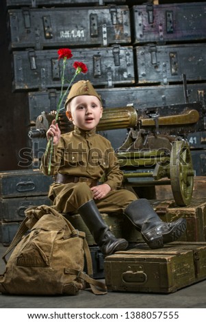 Picture to the day of victory. A little boy wearing a military uniform is holding a carnation flower. Retro style image