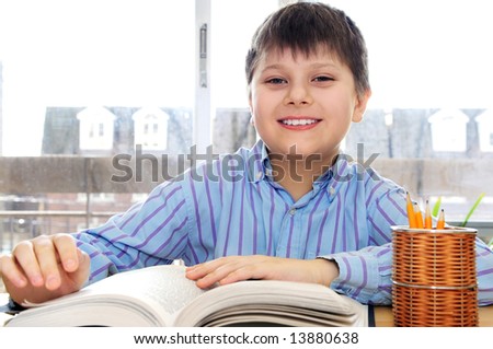 Happy school boy studying with a book