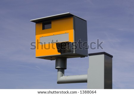Bright yellow speed trap camera on grey / gray metal post. Blue sky background.