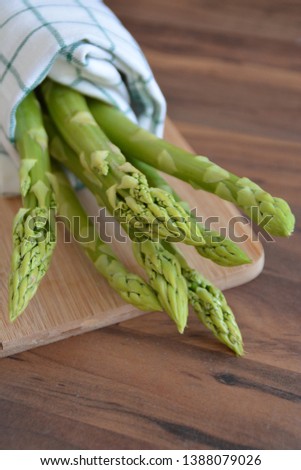 A bunch of green asparagus is uncooked on a dark marble surface