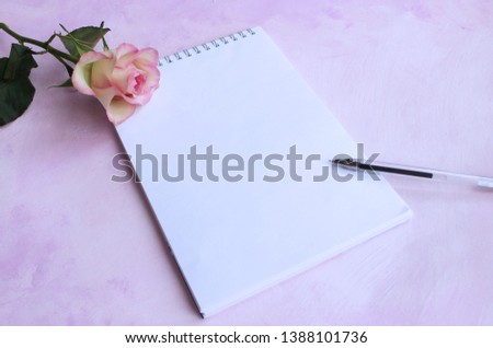 Pink rose and Notepad on light pink background.