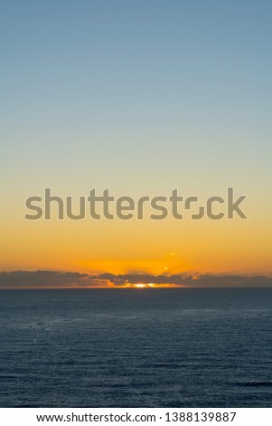 Sunrise over the ocean, sun is hidden behind the clouds