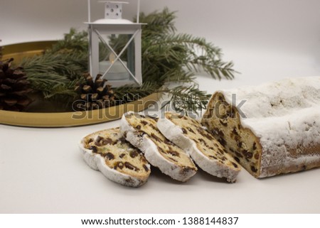 The three slices and the main part of Stollen with Christmas ornaments on a white background. Traditional German Christmas cake with marzipan and dried fruits.