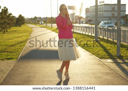 Portrait of beautiful blond girl posing for photo at the street walk