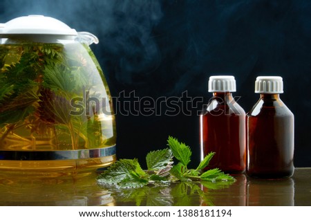 Tea teapot of fresh nettle and nettle leaves in a medical environment on a black background
