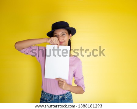 Close up portrait of positive laughing woman smiling and holding white big mockup poster isolated on yellow background 