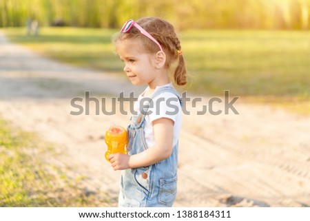 Summer season. Little Caucasian girl walks on nature dressed in denim overalls. Children's fashion. childhood