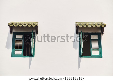 Windows with vintage shutters against a white wall.