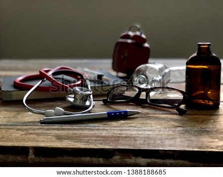 Health care and medical concept.Medical Cardiologist or Stethoscope,syringe,red alarm clock and eyes glasses,on empty old wood plank,dimly light.Rustic still life and dark background.Selective focus.
