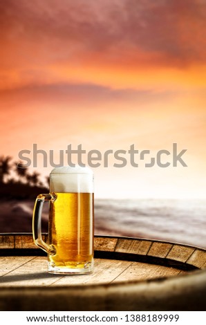 Cold fresh beer on wooden barrrel. Summer sunset time. Sea landscape with beach and palms. Free space for your bottle or text. 