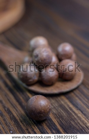 Macadamia nuts on the wooden spoon over the wooden table. Great photo for your needs. 