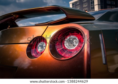 Close up of tail light detail of modern luxury sports car with reflection on chameleon paint after wash & wax. Rear view of supercar break led lights. Concept of car detailing and paint protection Royalty-Free Stock Photo #1388244629