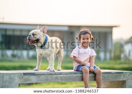 little girl is walk around with her cute french bulldog in the park.