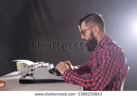 People and technology concept - Side view handsome man with beard working on typewriter over black background
