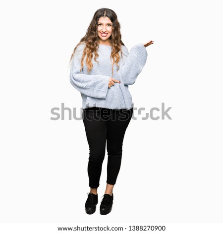 Young beautiful woman wearing winter sweater smiling cheerful presenting and pointing with palm of hand looking at the camera.