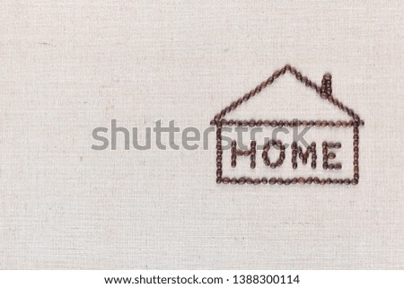 Home letter sign enclosed in house shape, made from roasted coffee beans isolated on creamy linea canvas, aligned middle right.