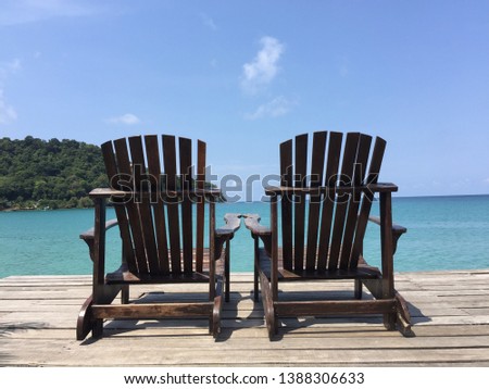 Picture of two wooden chairs without people sitting on the sea, Koh Kood, Thailand.Bright weather, strong sunlight, makes the sea look beautiful.
