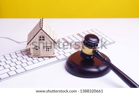 Conceptual image. Mini wooden house, wood gavel and keyboard isolated on yellow background.