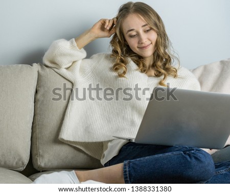 Girl sitting on sofa with laptope, hold big white mag cacao with marshmallow and listen music. Home cozy lifestile photo