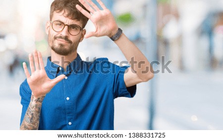 Young handsome man wearing glasses over isolated background Smiling doing frame using hands palms and fingers, camera perspective