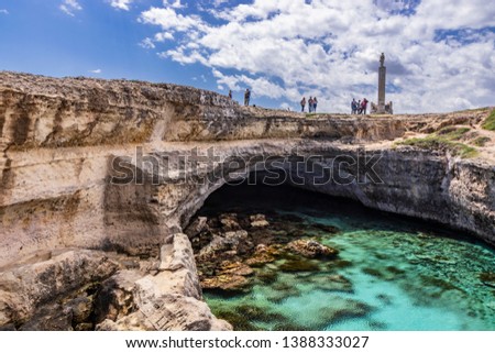 Archaeological site and tourist resort of Roca Vecchia, Puglia, Salento, Italy. Turquoise sea, clear blue sky, rocks, sun, in summer. The Cave of Poetry. Tourists take pictures and sunbathe.