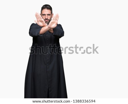 Young Christian priest over isolated background Rejection expression crossing arms and palms doing negative sign, angry face