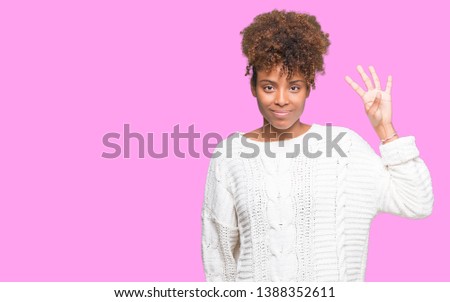 Beautiful young african american woman wearing winter sweater over isolated background showing and pointing up with fingers number four while smiling confident and happy.